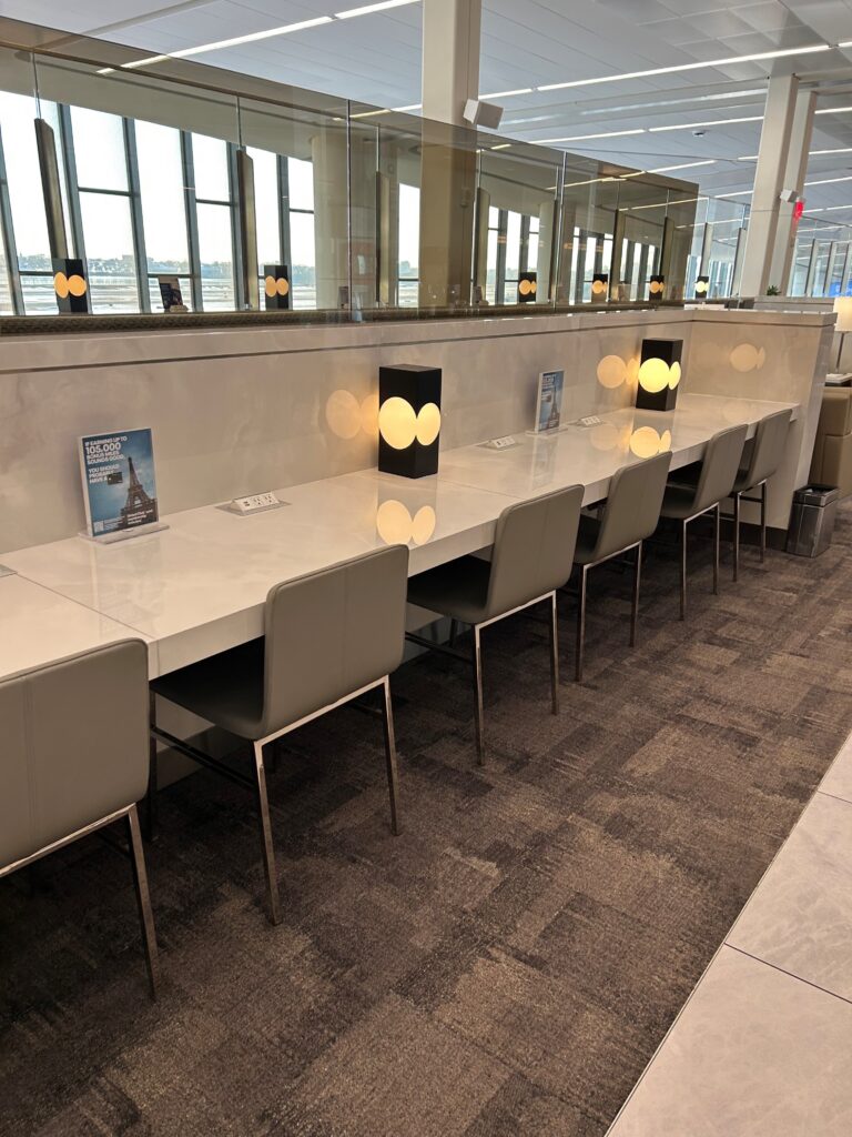 a long white table with chairs in a room with a large mirror