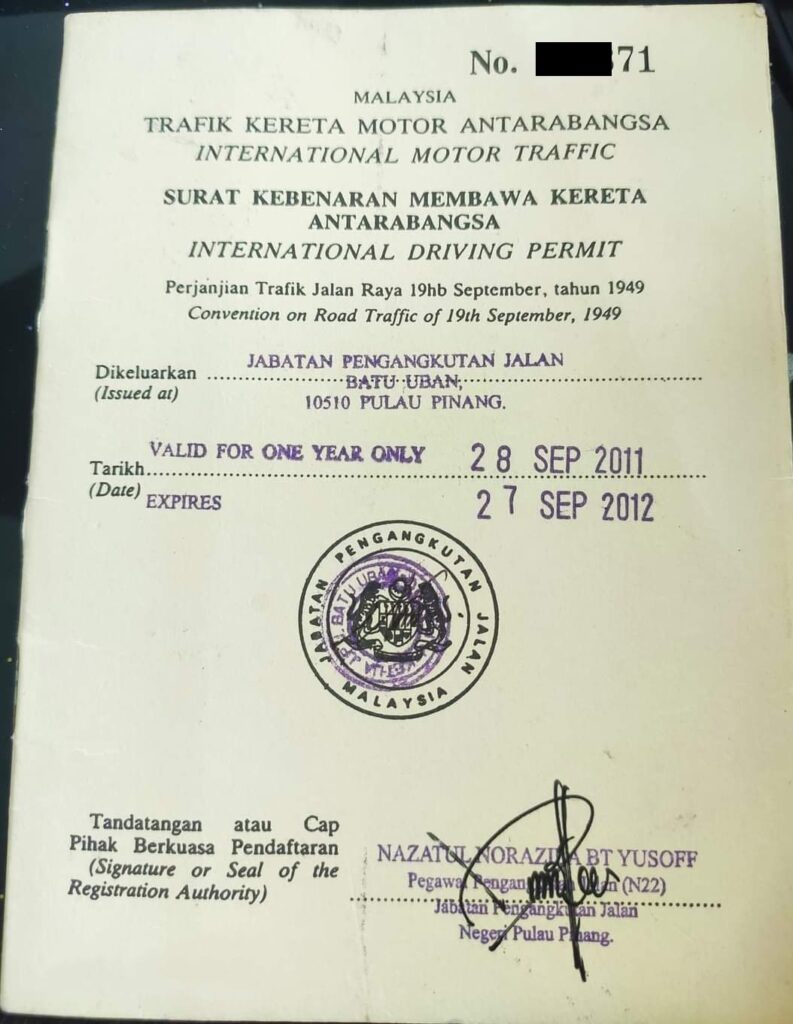 This image shows a Malaysian International Driving Permit. It includes text in both Malay and English, with details such as the issuing authority, location, and validity dates. There is an official stamp from the Jabatan Pengangkutan Jalan Malaysia and a signature from an official named Nazatul Norazizan Bt Yusoff. The permit is valid from September 28, 2011, to September 27, 2012.