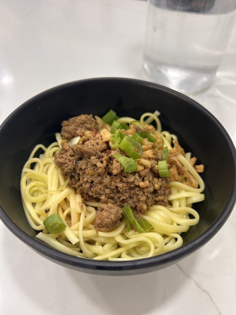 a bowl of noodles with meat and green onions