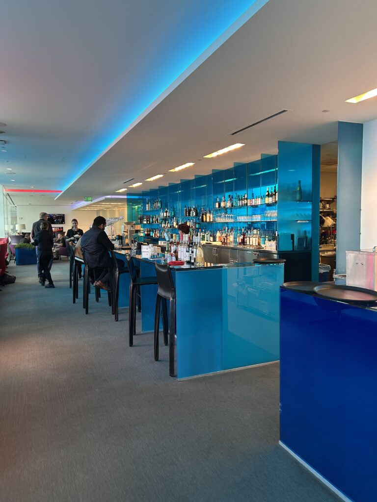 a bar with blue shelves and people sitting at the bar