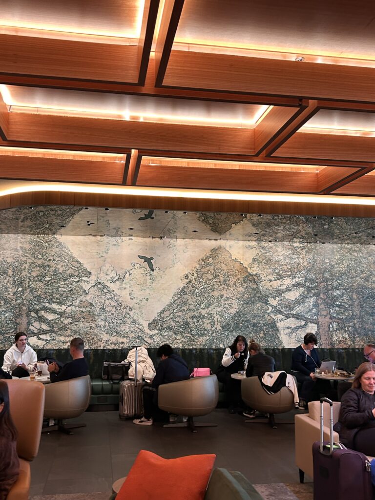 people sitting at tables in a room with a large wall and a painting on the wall