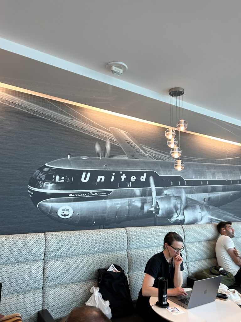 people sitting on a couch in a room with a large airplane on the wall