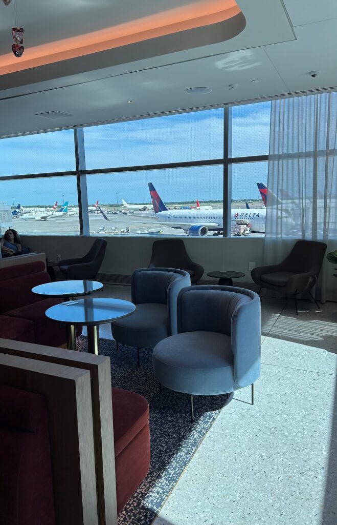 a room with chairs and tables and chairs and a window with airplanes in the background