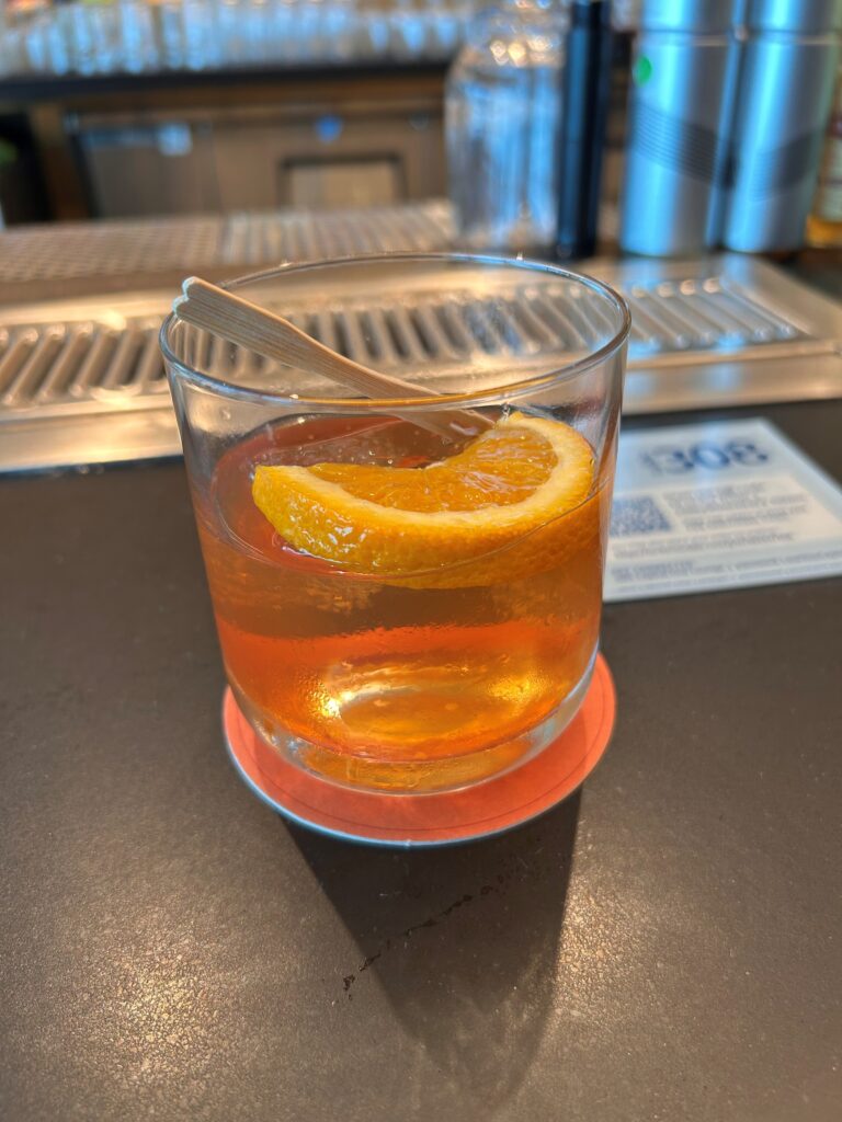 a glass of drink with a slice of orange on a counter