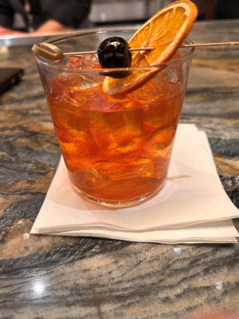 a glass with orange liquid and a fruit on top