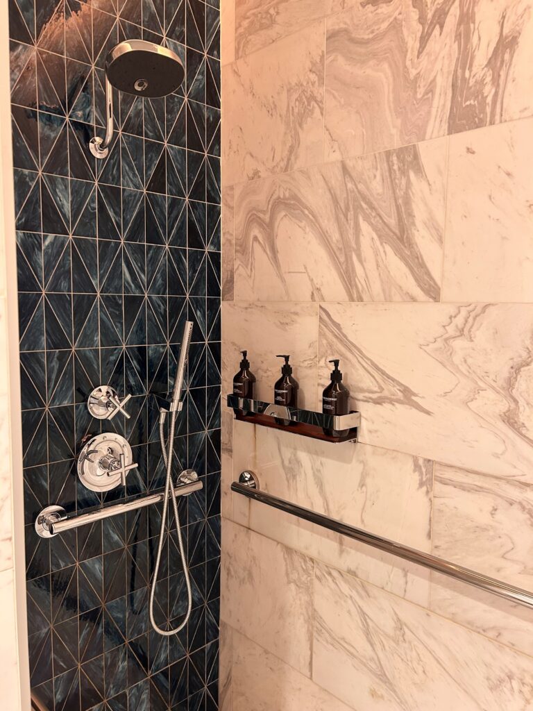 a shower with a tile wall and a shower head