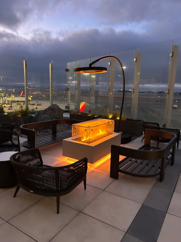 a fire pit with a lamp and chairs on a patio
