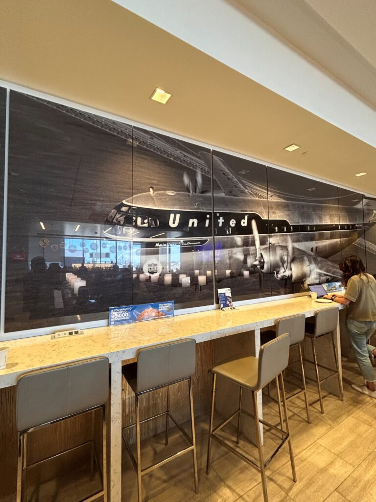 a woman standing at a counter in a room with a large poster of an airplane