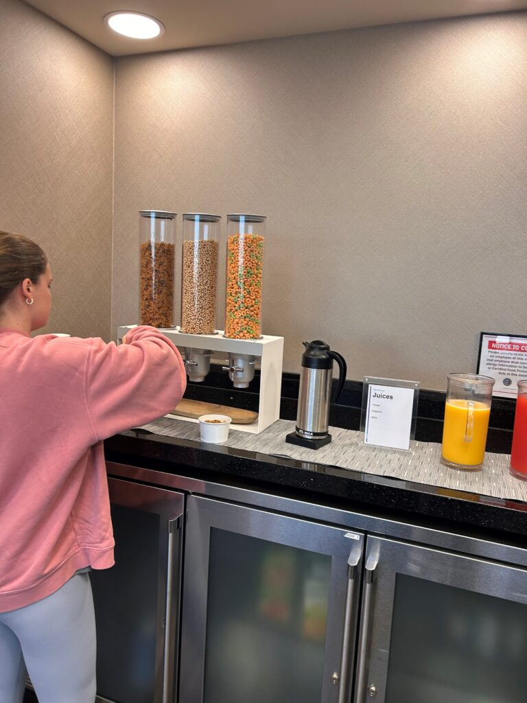 a woman standing at a counter with a variety of cereals in containers