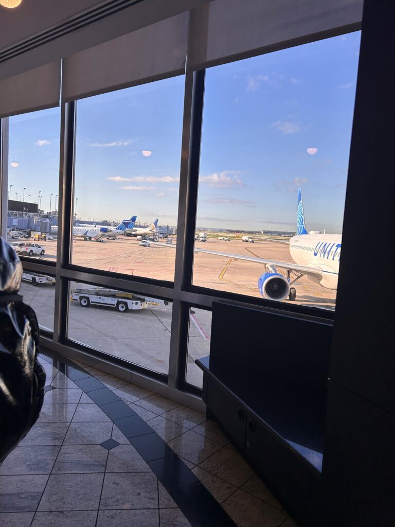 a window with a view of airplanes and trucks