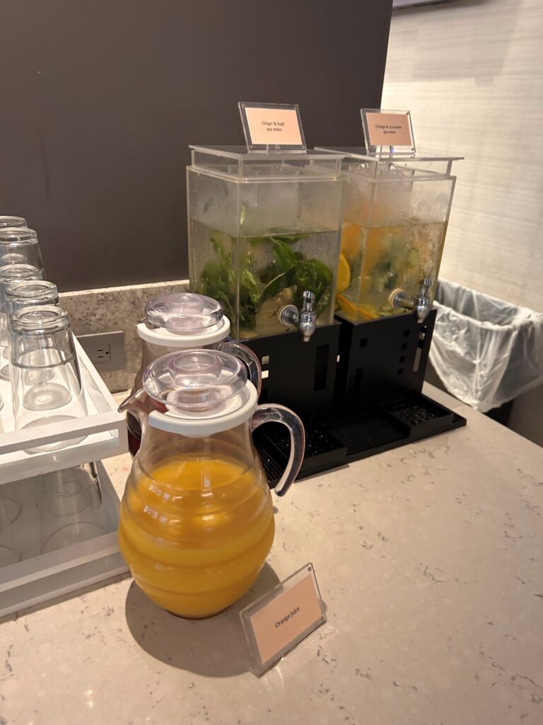 a group of water dispensers with orange juice in a pitcher