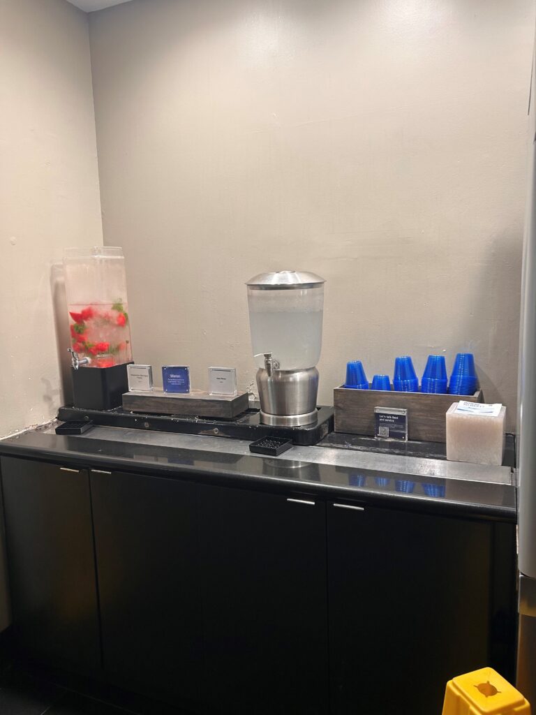 a black counter with a drink dispenser and blue cups