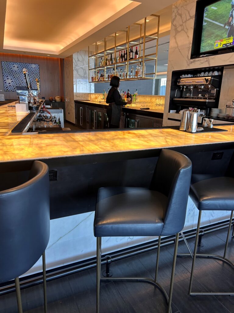a bar with chairs and a person behind it