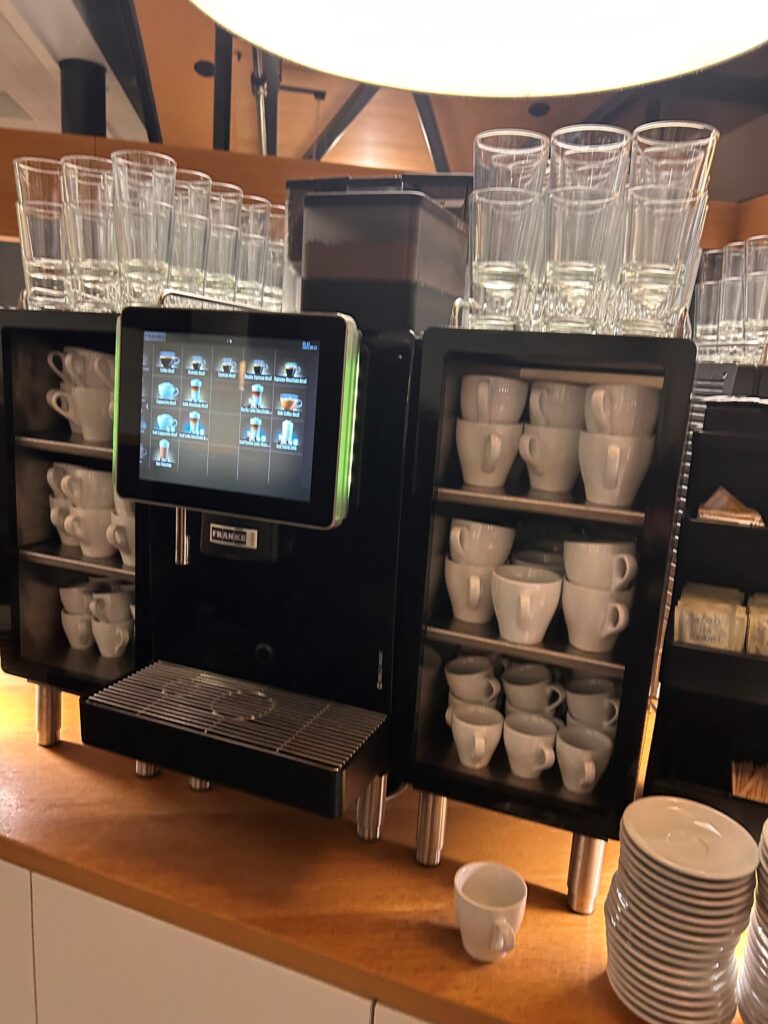 a coffee machine with a screen and cups on shelves