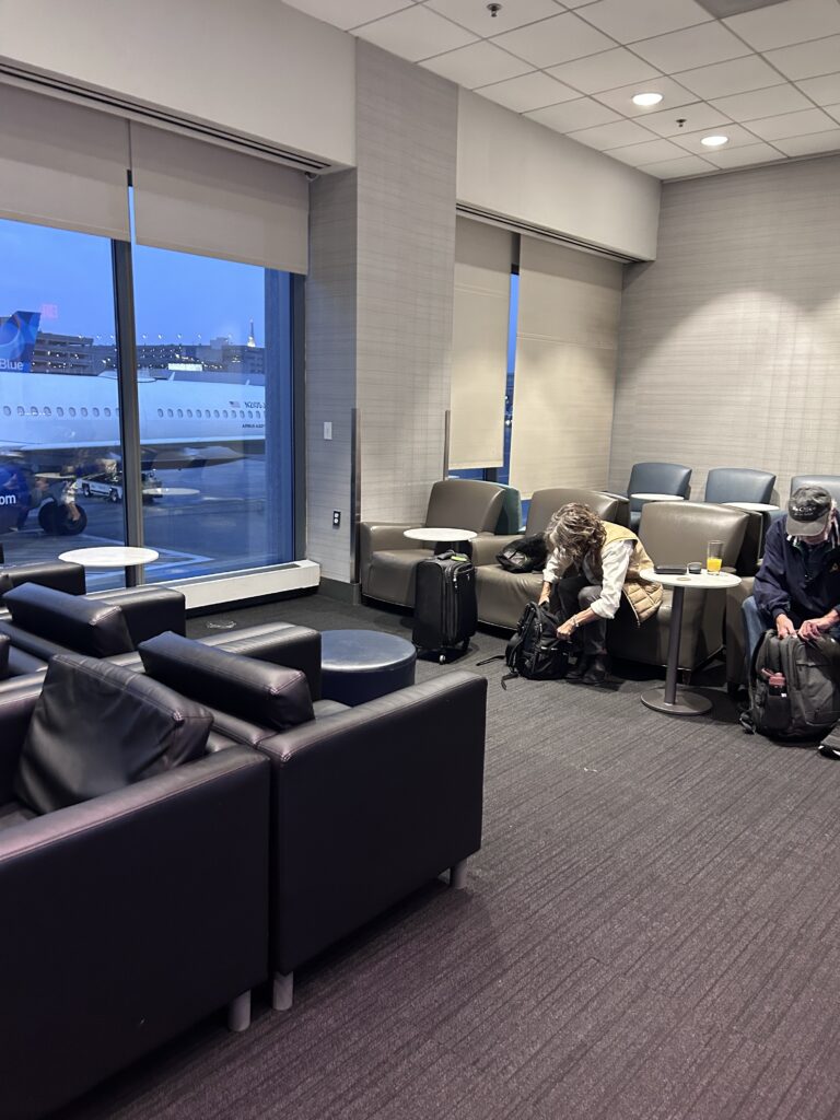 a group of people sitting in a lounge area with chairs and a table
