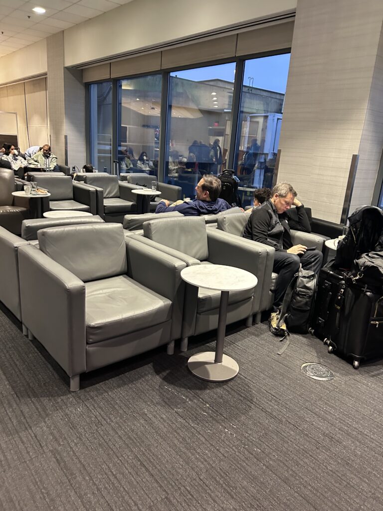 people sitting in a lounge area with chairs and luggage