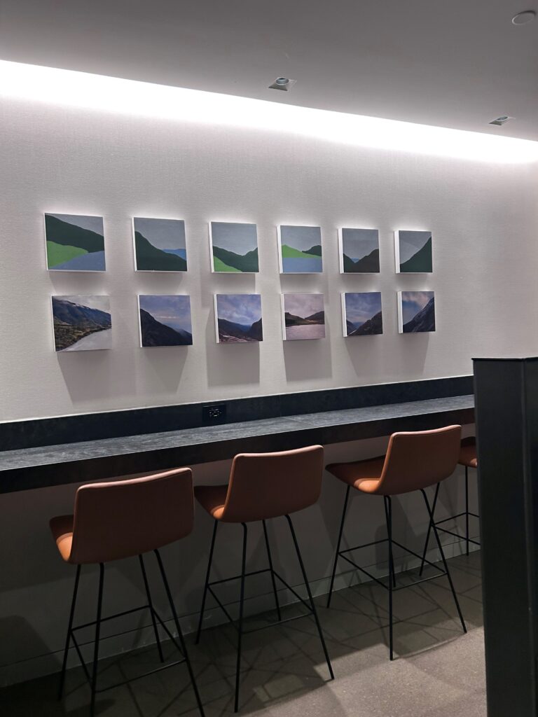 a row of chairs and a table with art on the wall