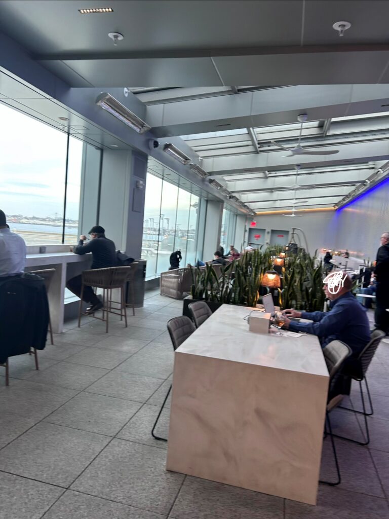 people sitting at tables in a room with large windows