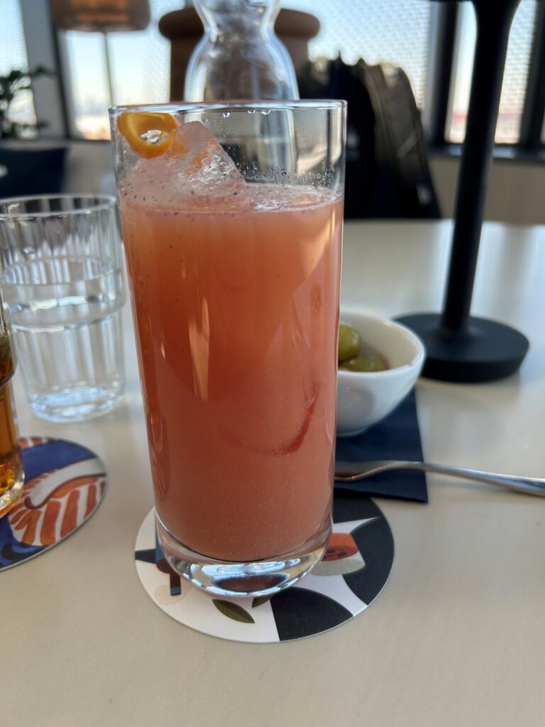 a glass of pink drink with a slice of orange on top