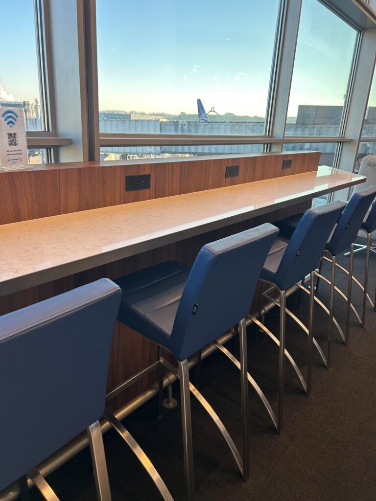 a row of blue chairs in a room with windows