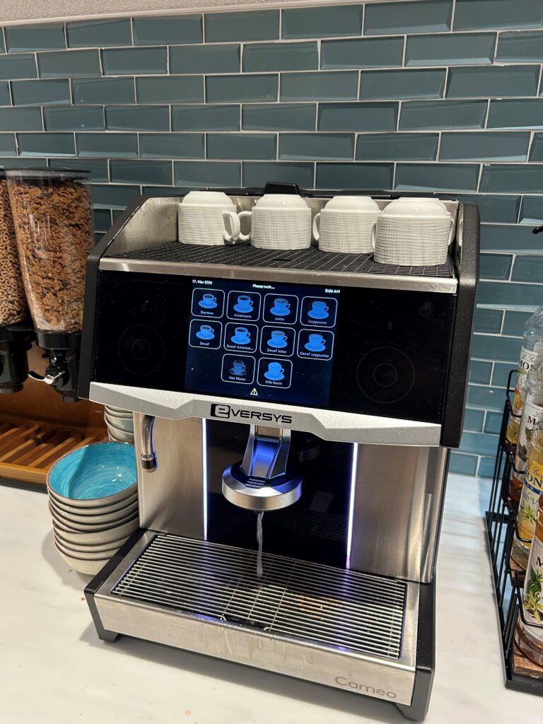 a coffee machine with a screen and cups on top